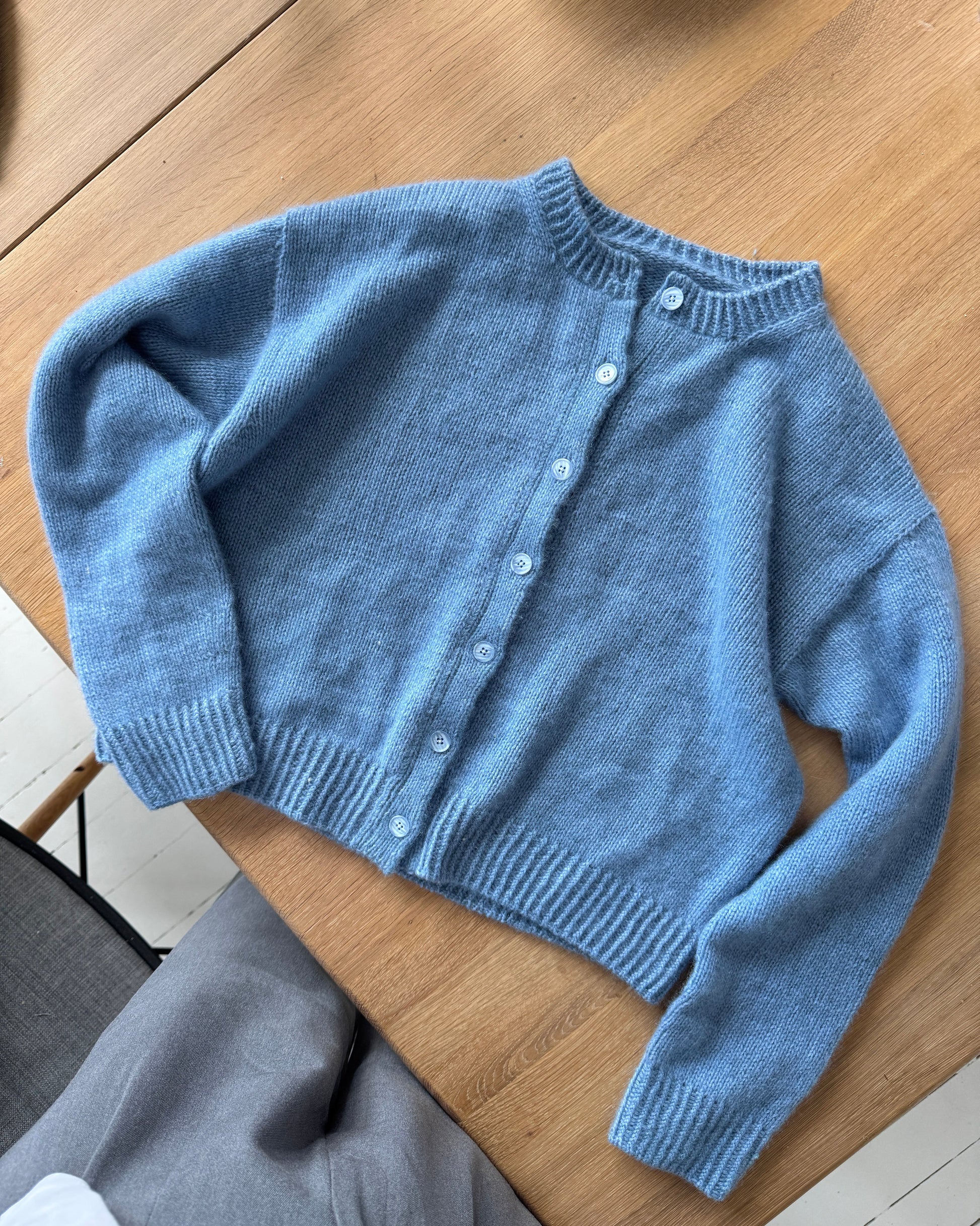 Blue knitted cardigan on a wooden surface